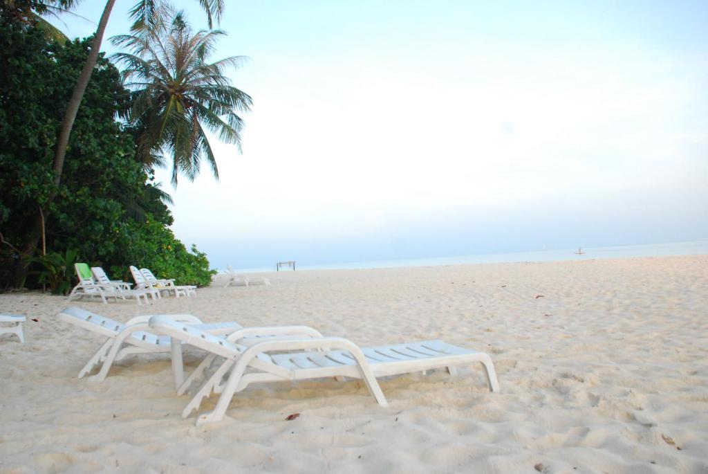 a group of lounge chairs on a beach at PRIV Fodhdhoo in Fodhdhoo