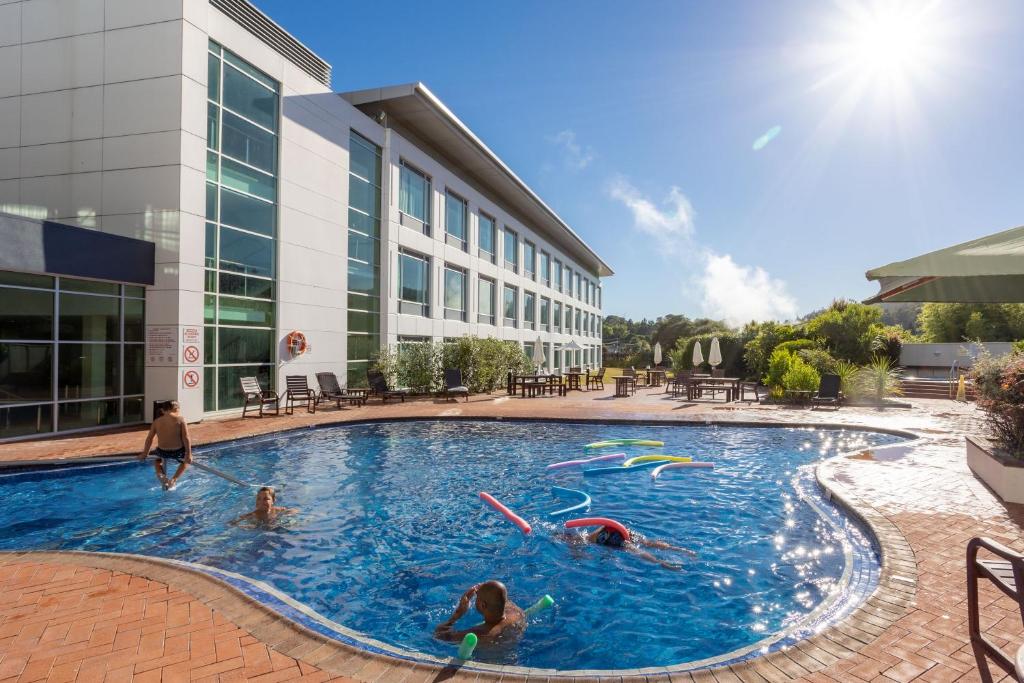 a swimming pool with people swimming in it at Rydges Rotorua formerly known as Holiday Inn Rotorua in Rotorua