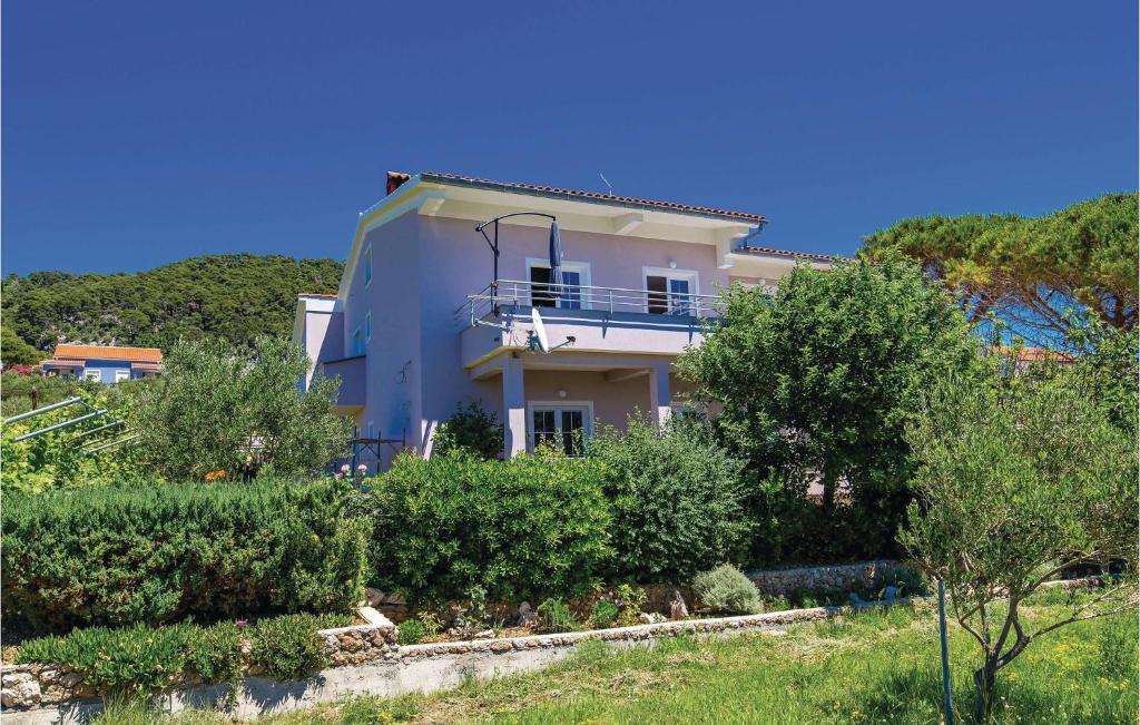a white house with a balcony and bushes at Amazing Apartment In Barbat Na Rabu in Barbat na Rabu