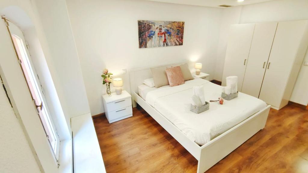 a white bedroom with a bed and a mirror at Hola Madrid Alojamiento Temporal in Madrid