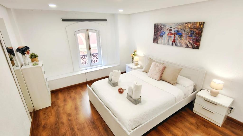 a white bedroom with a bed and a window at Hola Madrid in Madrid