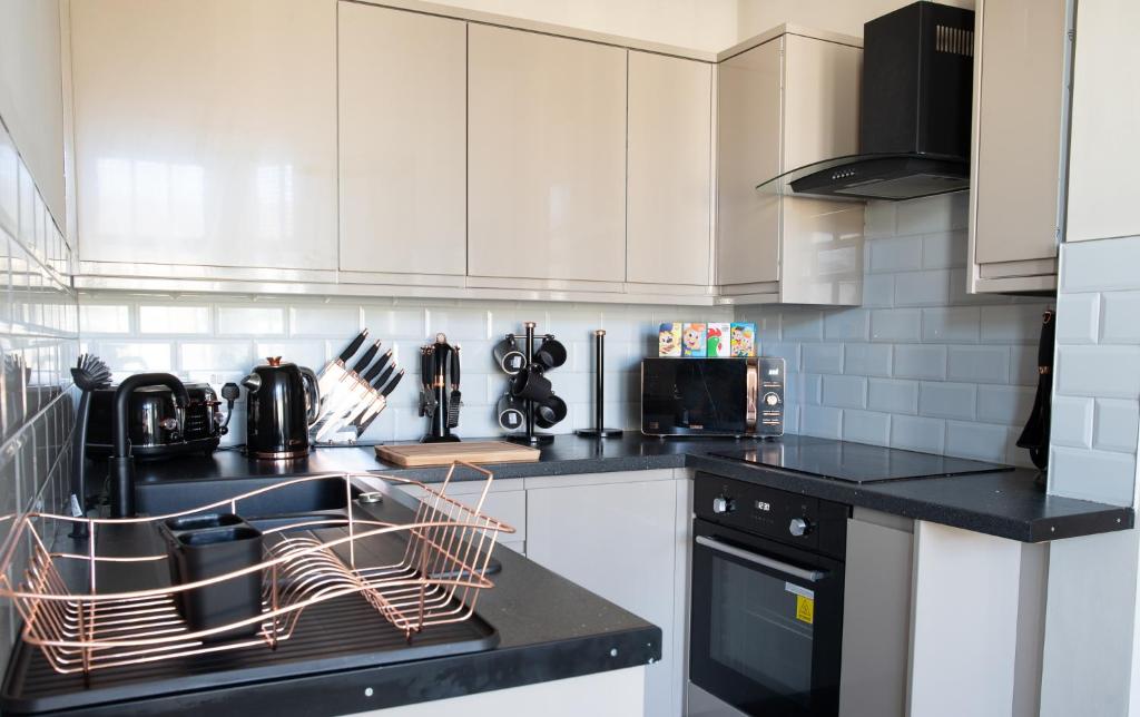a kitchen with white cabinets and a dish drying rack at Withnell Stays - Apartment Two - Retro Arcade Machine in Blackpool