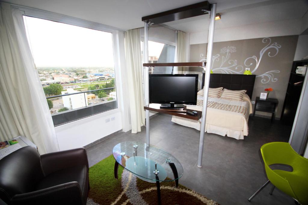 a living room with a bed and a tv and a couch at Hotel NEU 354 in Neuquén