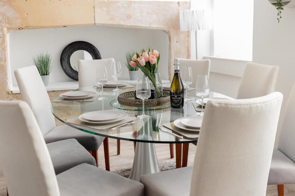 a dining room with a glass table and white chairs at Portland Place in Bath in Bath