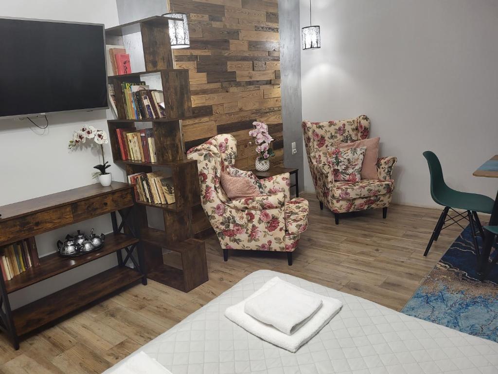 a living room with two chairs and a book shelf at Apartamenty GUSTO in Ostróda