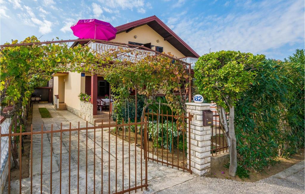 a house with a fence and a pink umbrella at Stunning Home In Sabunike-privlaka With 4 Bedrooms And Wifi in Nin