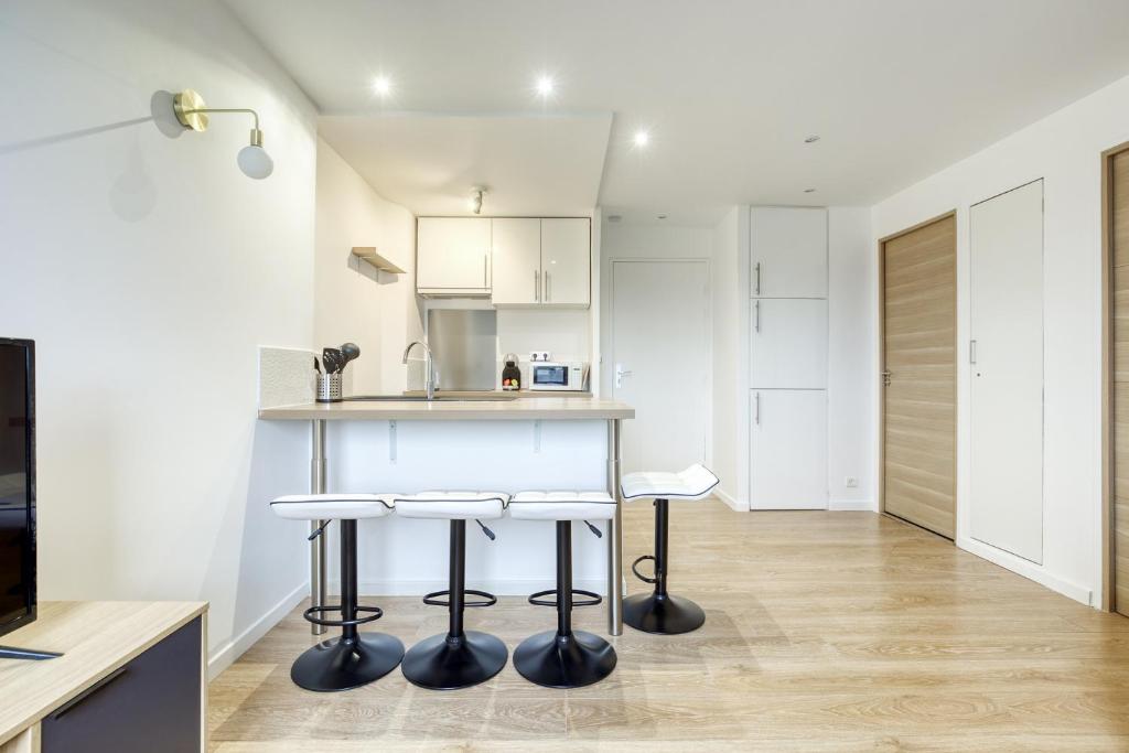 a kitchen with a counter and stools in a room at Très bel appartement 5pers - 3km-8mn Disneyland in Magny-le-Hongre