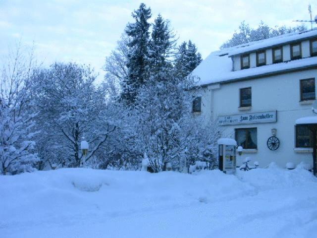 a building covered in snow with trees in the background at Waldpension zum Felsenkeller in Lichtenfels-Sachsenberg