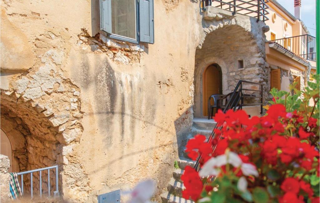 a stone building with red flowers in front of it at Gorgeous Apartment In Omisalj With Kitchen in Omišalj