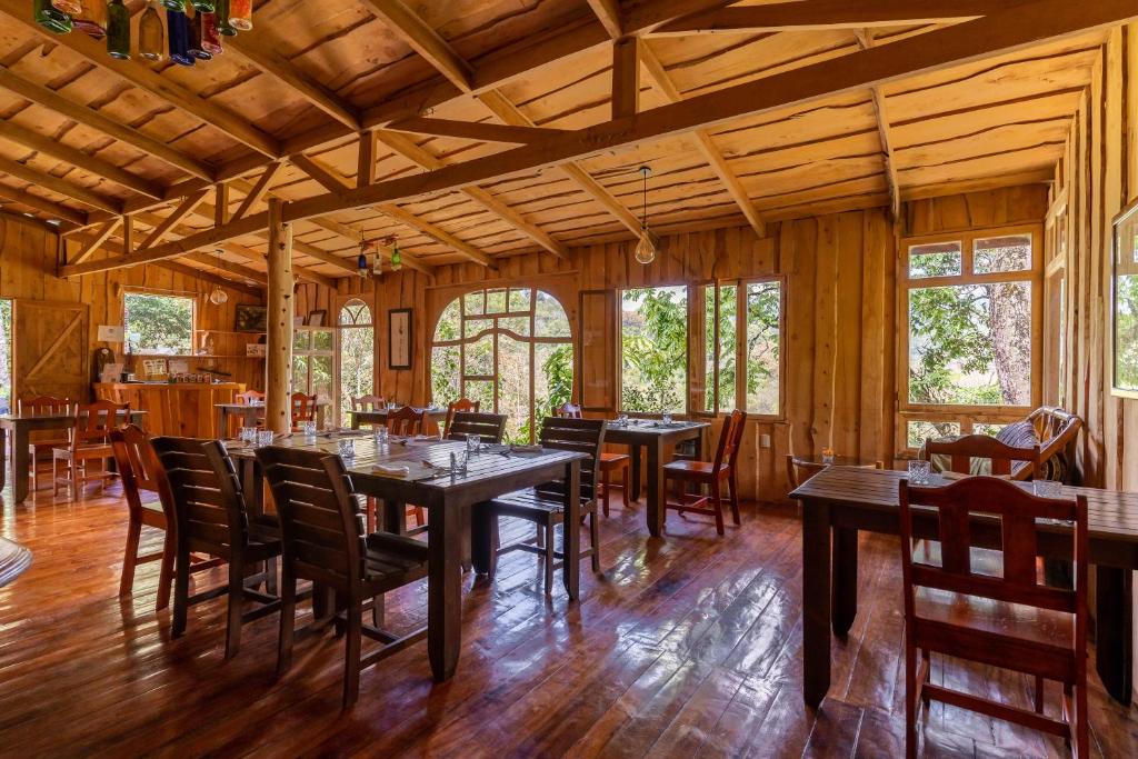 een eetkamer met houten vloeren en tafels en stoelen bij Cedrela Eco-Lodge & Restaurante in El Copey