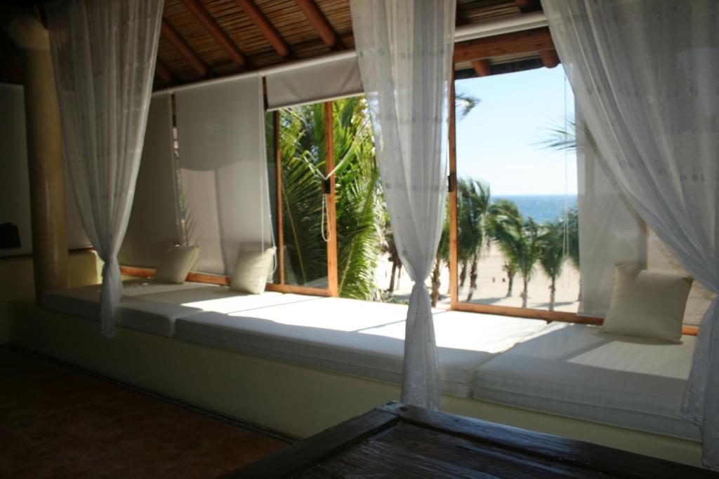 Cama en habitación con ventana grande en Casa Kaukan en Zihuatanejo