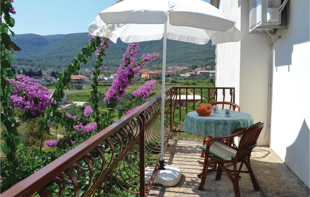 balkon ze stołem, parasolem i fioletowymi kwiatami w obiekcie Apartment Jelsa 07 w mieście Jelsa