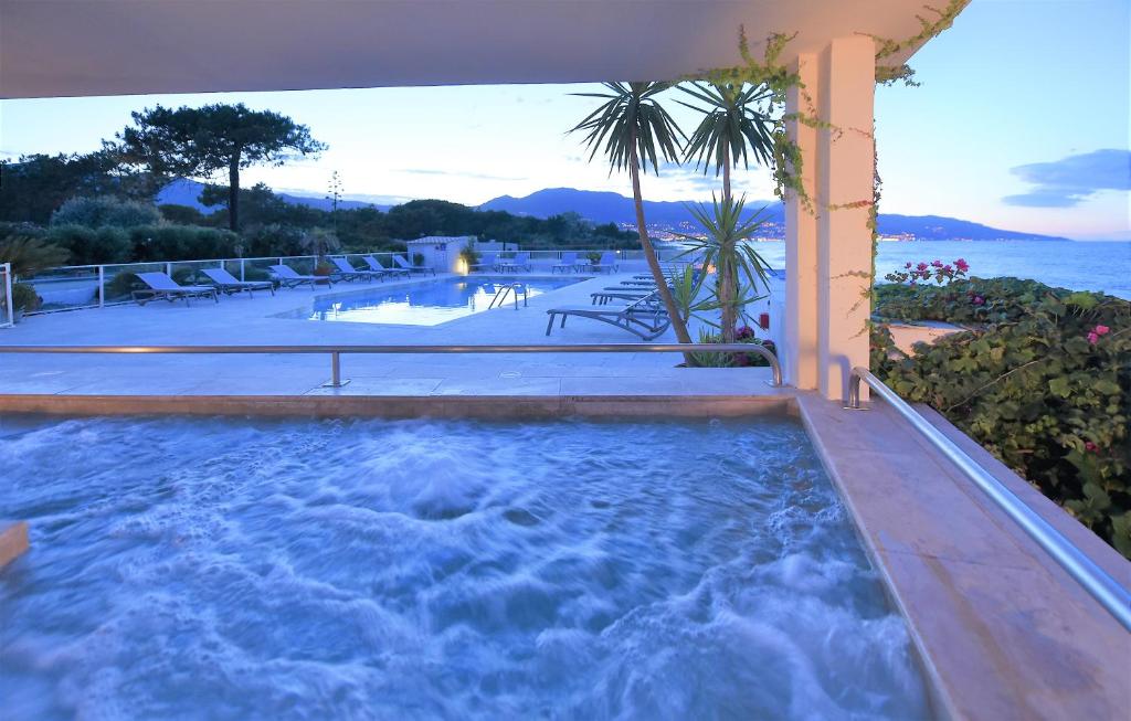 uma grande piscina de mergulho com cadeiras e o oceano em Hôtel Pineto em Biguglia