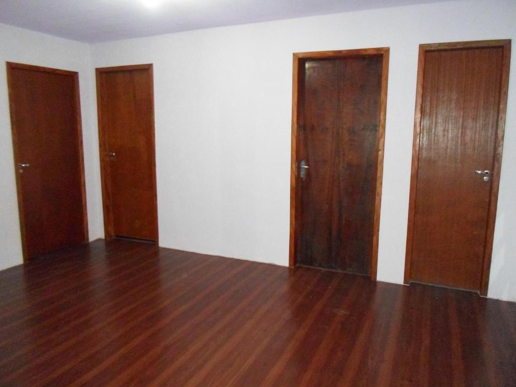 Habitación vacía con 3 puertas y suelo de madera. en Assel Pousada Xaxim, en Curitiba