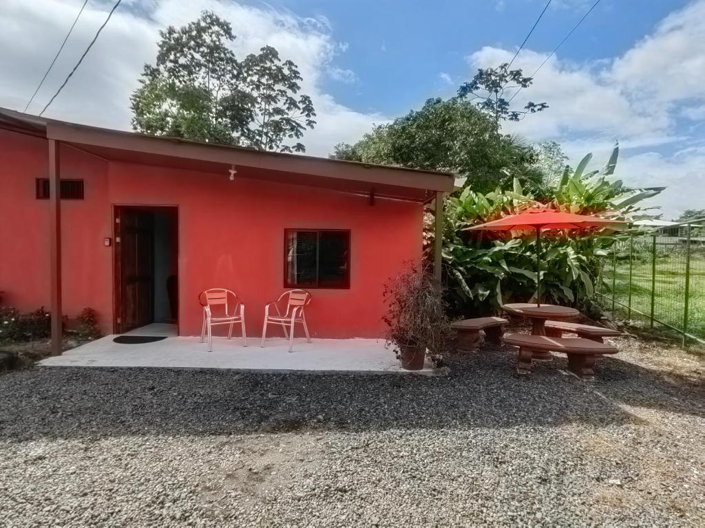 uma casa vermelha com duas cadeiras, uma mesa e um guarda-sol em Pura Vida Aparment - Downtown La Fortuna em La Fortuna