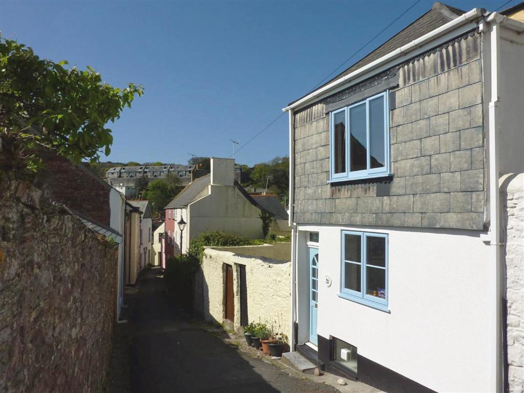 an alley with a white house and a building at Chough Cottage in Cawsand