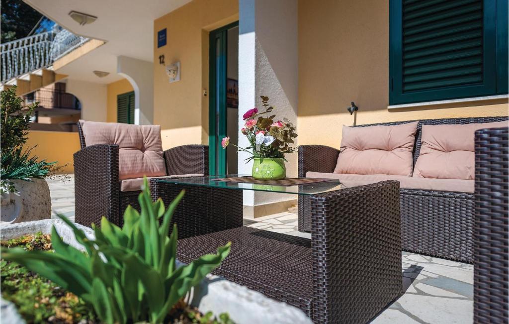 eine Terrasse mit Korbmöbeln und einem Glastisch in der Unterkunft Cozy Apartment In Rogoznica With Wifi in Rogoznica