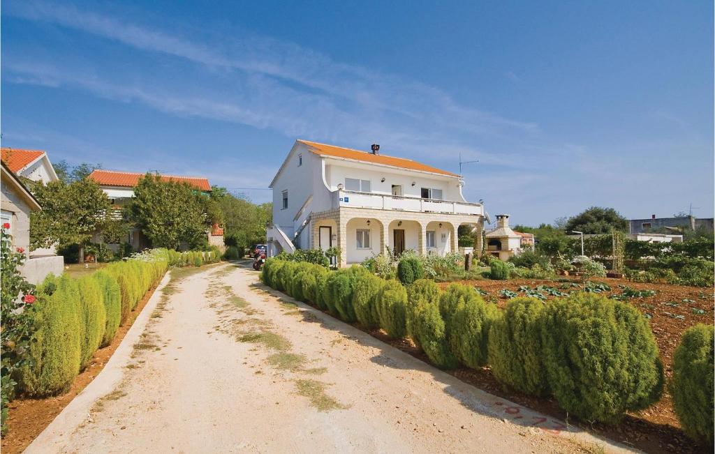 a white house with a row of bushes on a dirt road at Nice Apartment In Vir With 3 Bedrooms in Vir