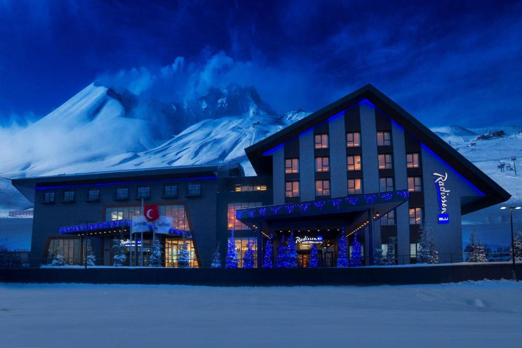 a hotel with a snow covered mountain in the background at Radisson Blu Hotel, Mount Erciyes in Erciyes
