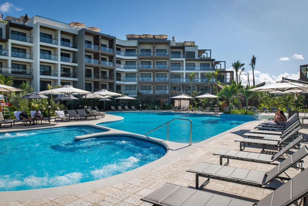 een zwembad met stoelen en een hotel bij Ventus Ha at Marina El Cid Spa & Beach Resort - All Inclusive in Puerto Morelos