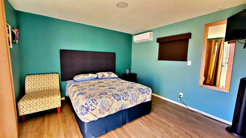 1 dormitorio con paredes azules, 1 cama y 1 silla en Popotla Room #2, en Plan Libertador