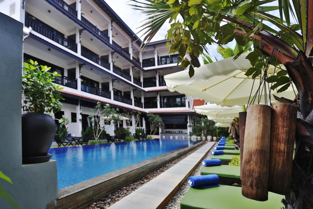 暹粒的住宿－高棉公館精品酒店，酒店游泳池设有躺椅和遮阳伞