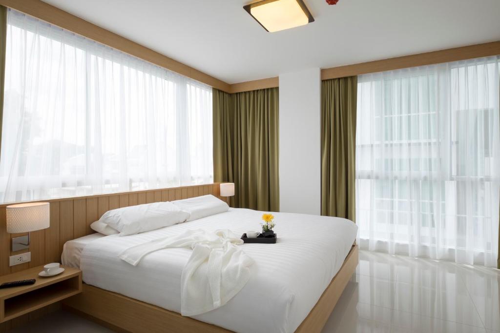 1 dormitorio con 1 cama blanca grande y ventanas en Modern Thai Suites, en Phuket