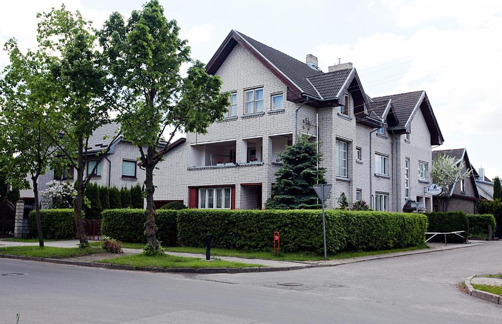 duży biały dom z drzewem przed nim w obiekcie Fortūna Guest House w Kłajpedzie