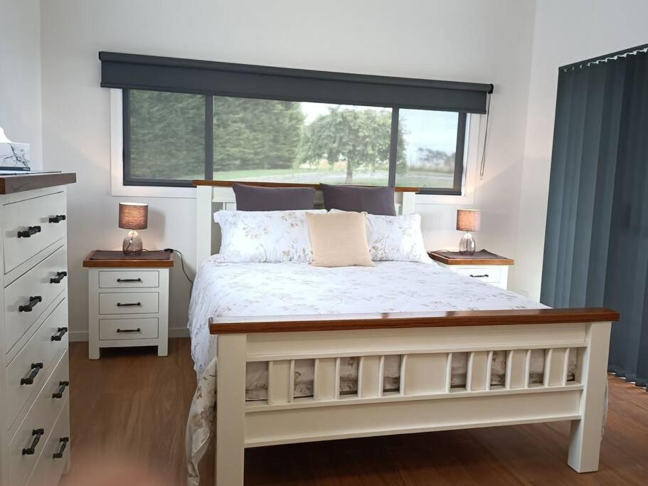 een slaapkamer met een wit bed en een groot raam bij Spiritwood, BnB for 2 in a quiet rural setting 
