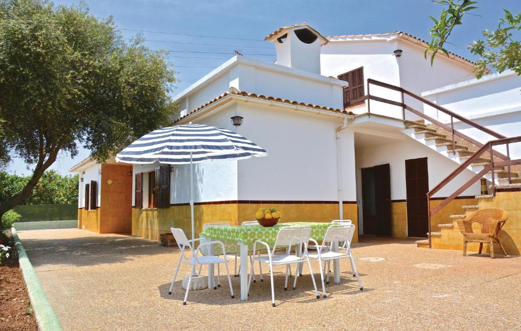 a table and chairs with an umbrella in front of a house at 3 Bedroom Awesome Home In Porto Cristo in Porto Cristo