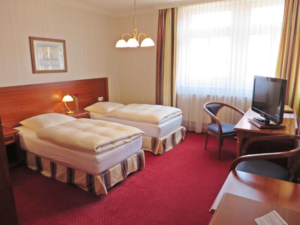 a hotel room with two beds and a television at Hotel Roseneck in Hagenow