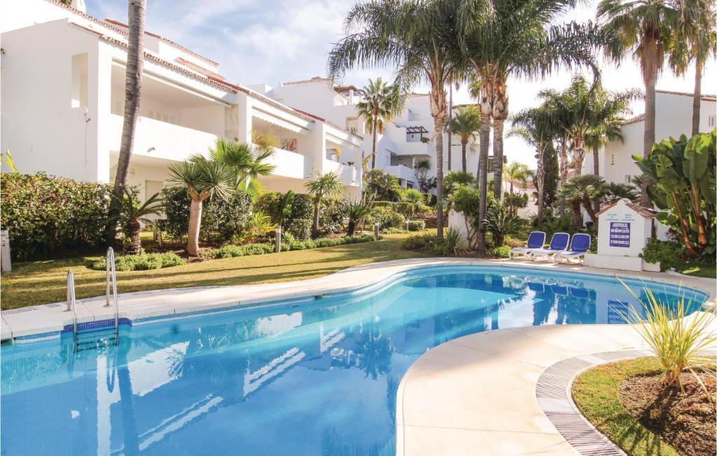 マルベーリャにあるAmazing Apartment In Marbella With Outdoor Swimming Poolのヤシの木が茂る建物の前にあるスイミングプール
