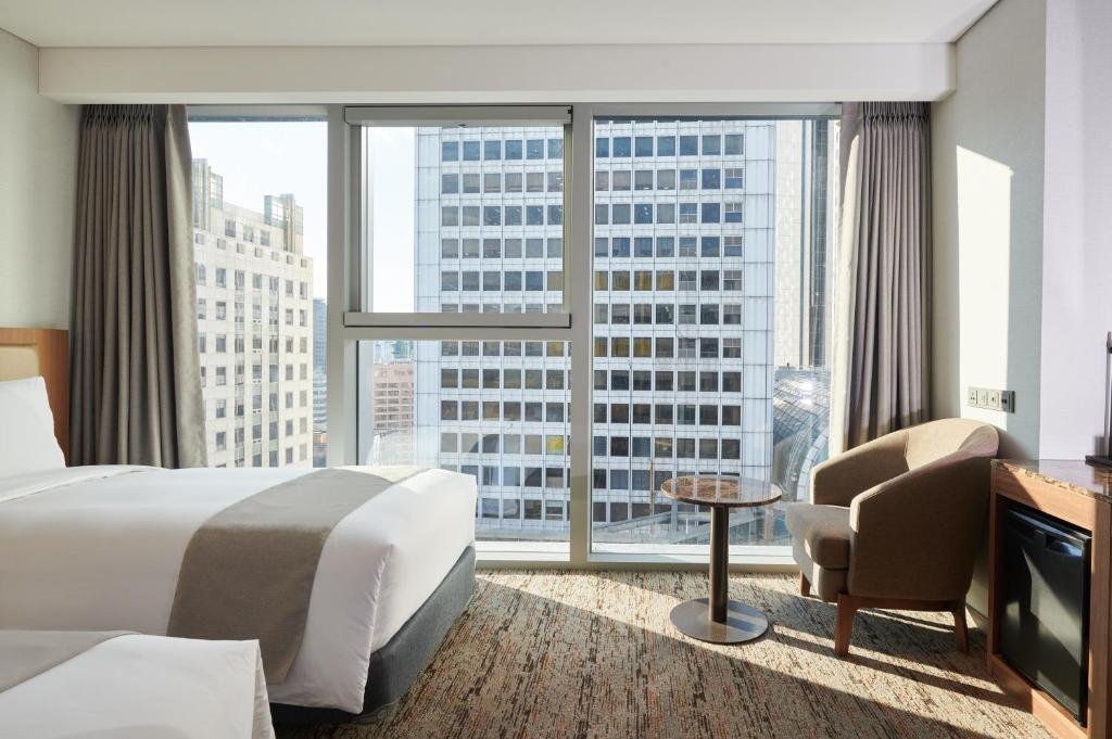 ein Hotelzimmer mit einem Bett und einem großen Fenster in der Unterkunft Stanford Hotel Myeongdong in Seoul