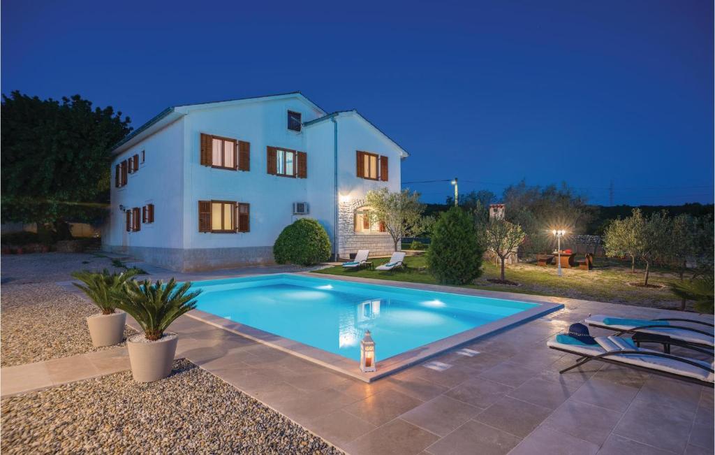 a villa with a swimming pool in front of a house at Amazing Apartment In Krk With Outdoor Swimming Pool in Vrh