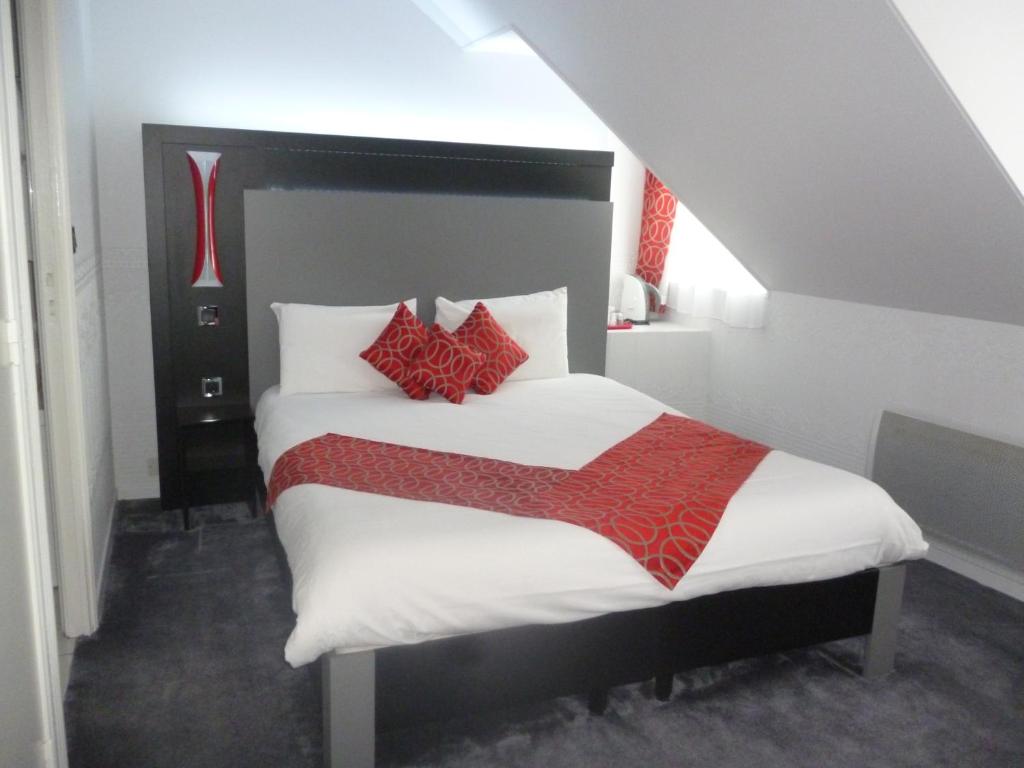 a bedroom with a large bed with red pillows at Auberge bretonne in Châteaubriant