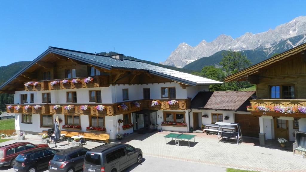 a large building with cars parked in a parking lot at Blasbichlerhof in Ramsau am Dachstein