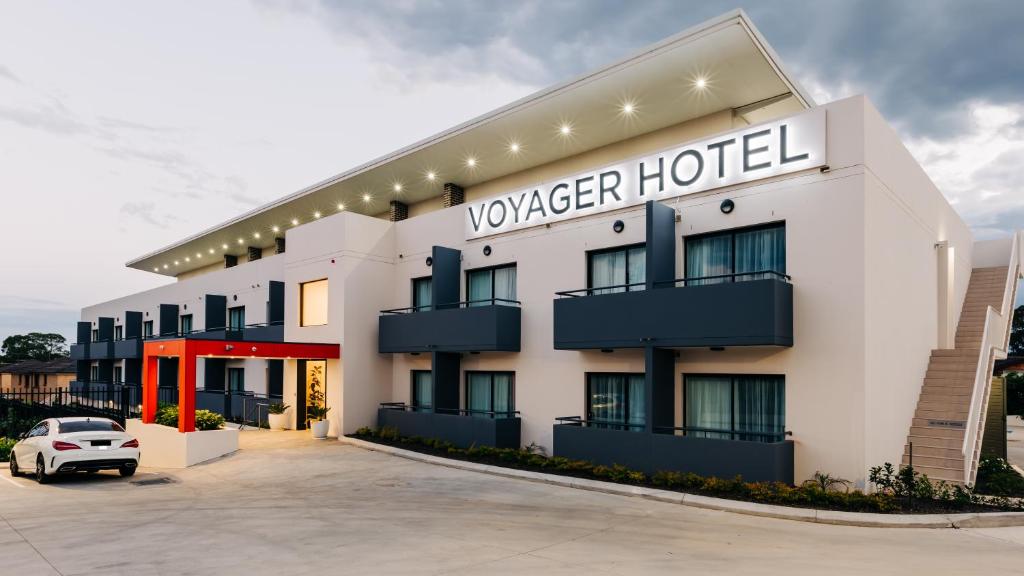 a hotel exterior with a car parked in a parking lot at Voyager Motel in Wallgrove