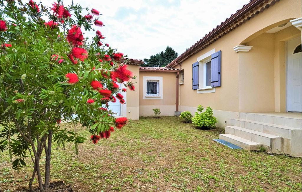 a house with a tree with red flowers in the yard at Beautiful Home In Mornas With 4 Bedrooms, Private Swimming Pool And Outdoor Swimming Pool in Mornas