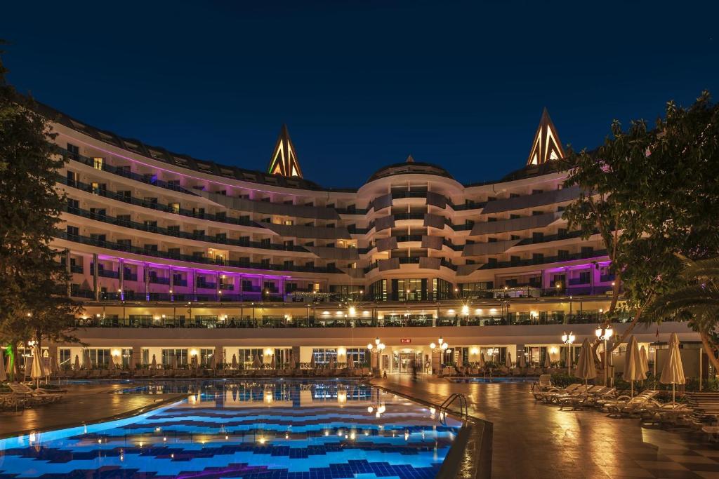 a large building with a pool at night at Botanik Platinum Hotel in Okurcalar