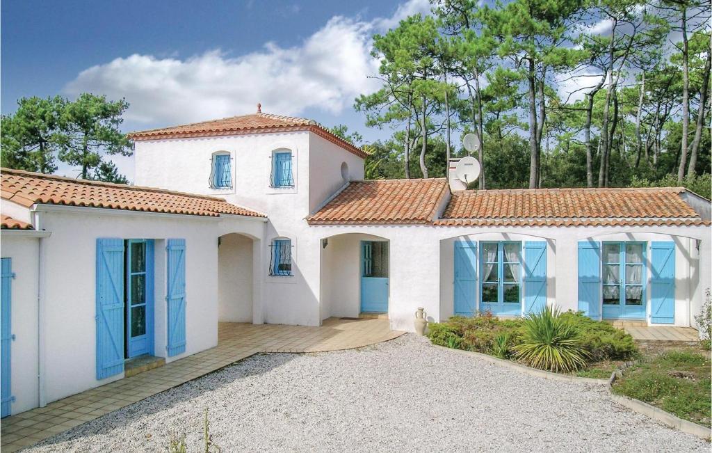 une maison blanche avec des portes bleues dans une allée. dans l'établissement Awesome Home In La Tranche Sur Mer With 3 Bedrooms, à La Tranche-sur-Mer