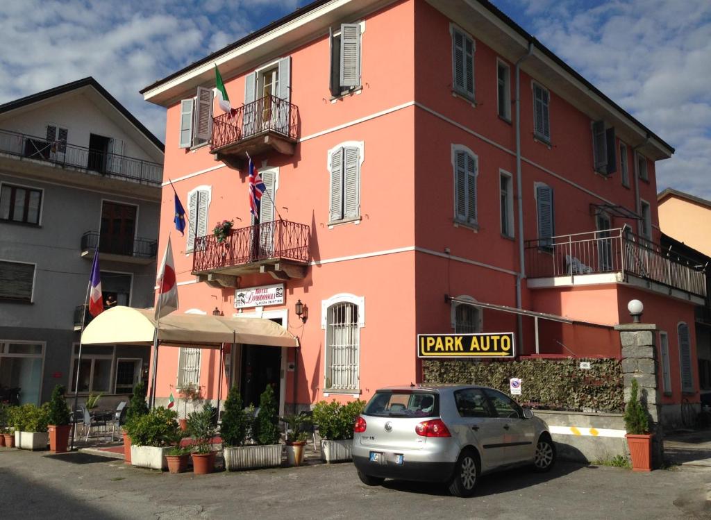 ein Auto, das vor einem rosa Gebäude parkt in der Unterkunft Hotel Domodossola in Domodossola