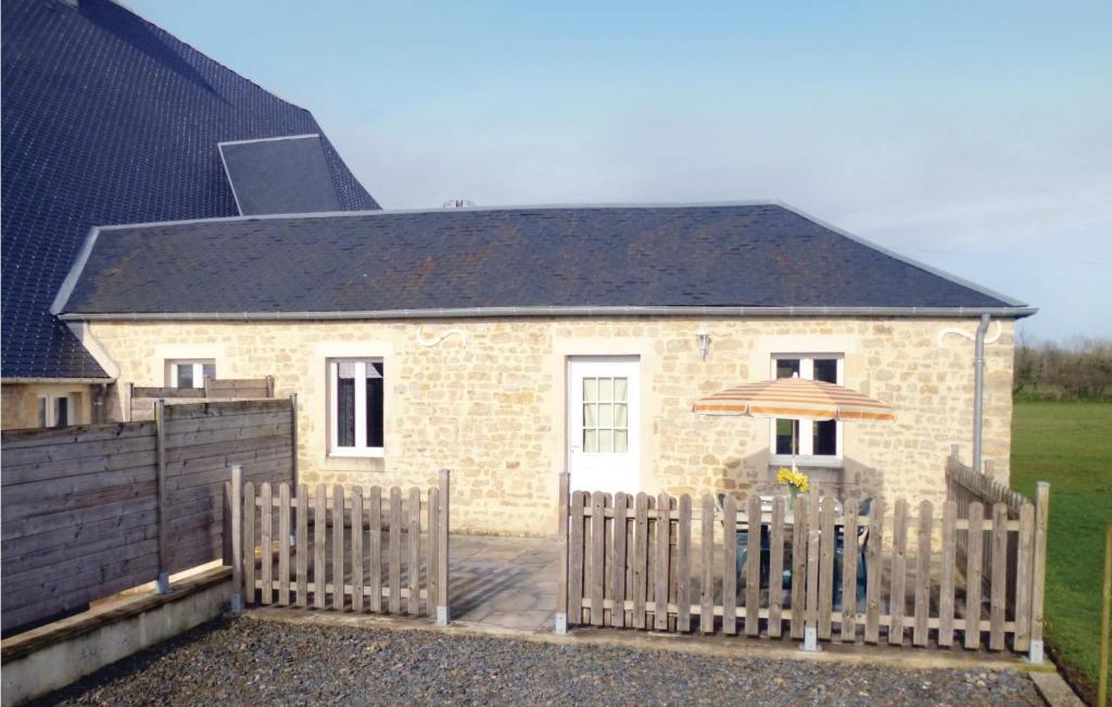une maison en briques avec une clôture en bois et un parasol dans l'établissement Holiday Home Acqueville - Les Pavillons O-795, à Deux-Jumeaux