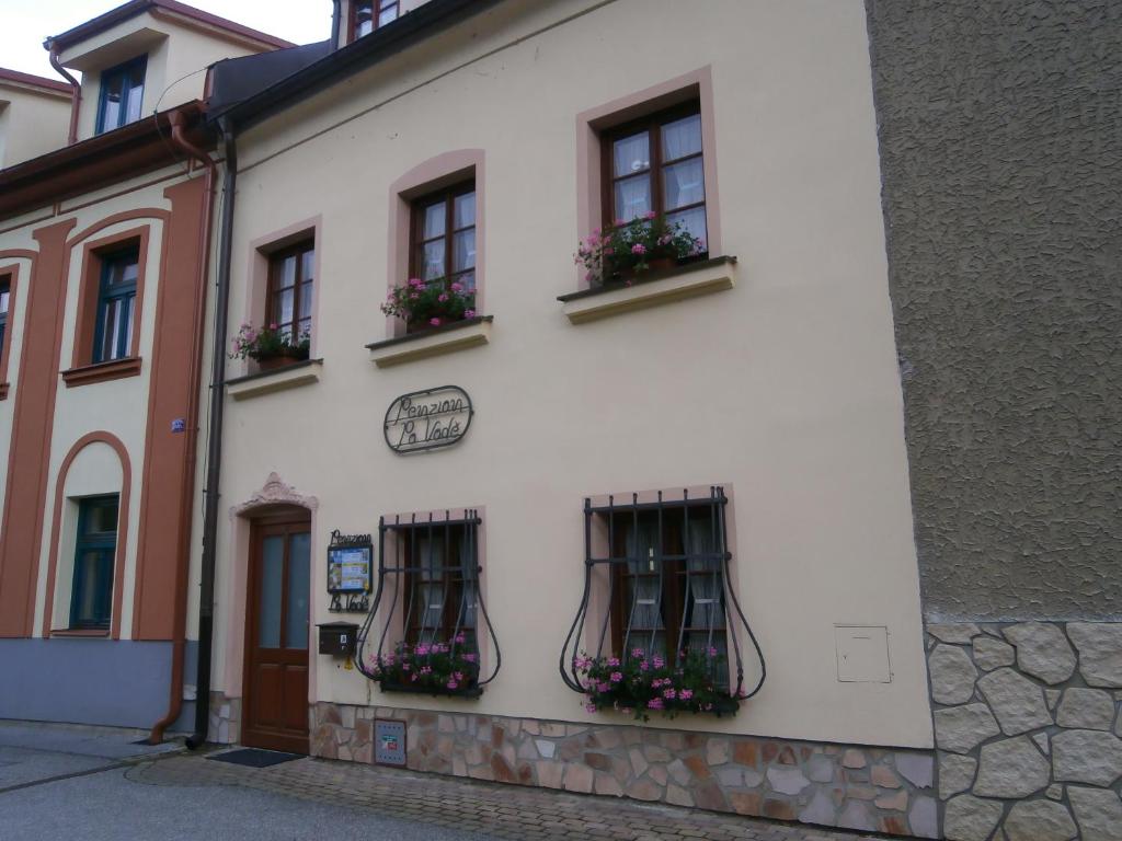 a white building with two windows with flower boxes at Penzion Po Vode in Český Krumlov