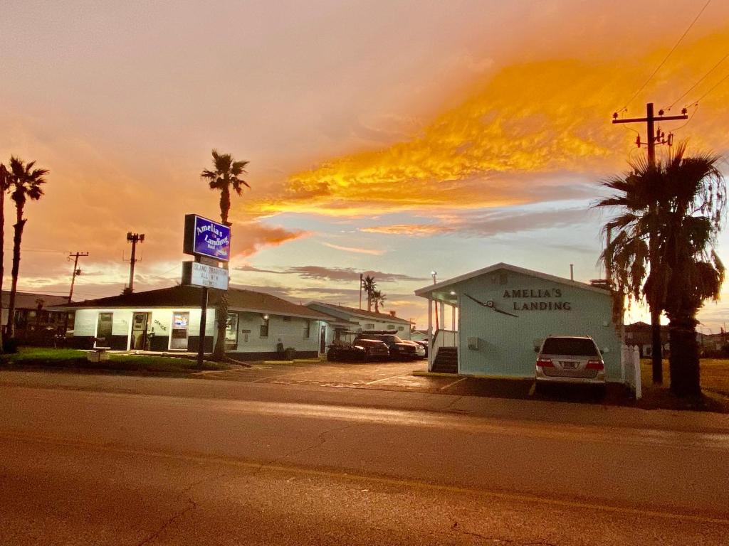 a building on the side of a street with palm trees at Amelia's Landing in Port Aransas