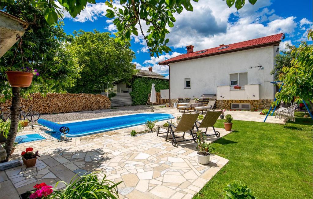 a pool in a backyard with chairs and a blue slide at 2 Bedroom Cozy Apartment In Drazice in Dražice