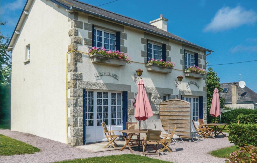a house with chairs and umbrellas in front of it at Two-Bedroom Holiday Home In Saint Cast Le Guildo in LʼIsle-Saint-Cast
