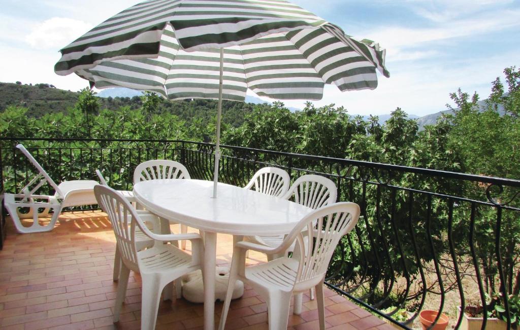 un tavolo e sedie su un balcone con ombrellone di 3 Bedroom Amazing Home In Valle Di Rostino a Casapitti
