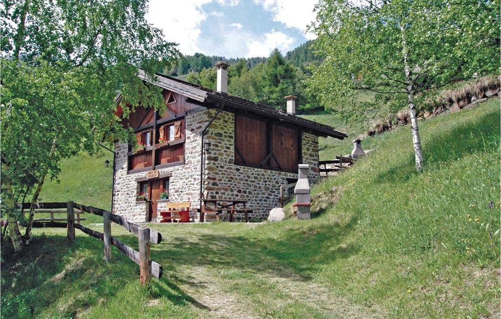 una pequeña casa de piedra en una colina con una valla en Mas Roncal 5, en Celledizzo