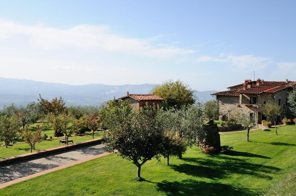 - une vue sur un jardin arboré et un bâtiment dans l'établissement Agriturismo Villa Iris, à Castelfranco di Sopra