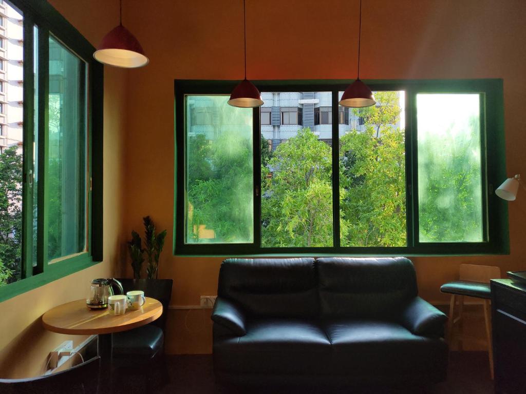 a room with a couch and a table and windows at Foshan Cuba Youth Hostel in Foshan